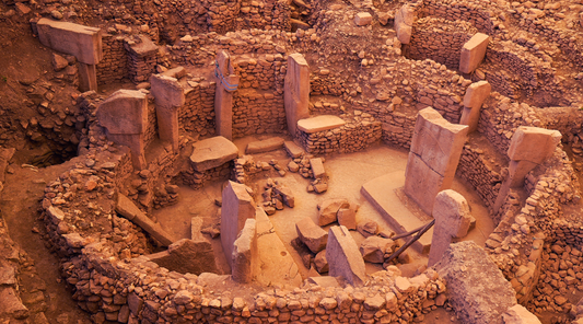 Archaeological view of Göbekli Tepe in Turkey showing circular stone enclosures and massive carved pillars dating back over 11,000 years.