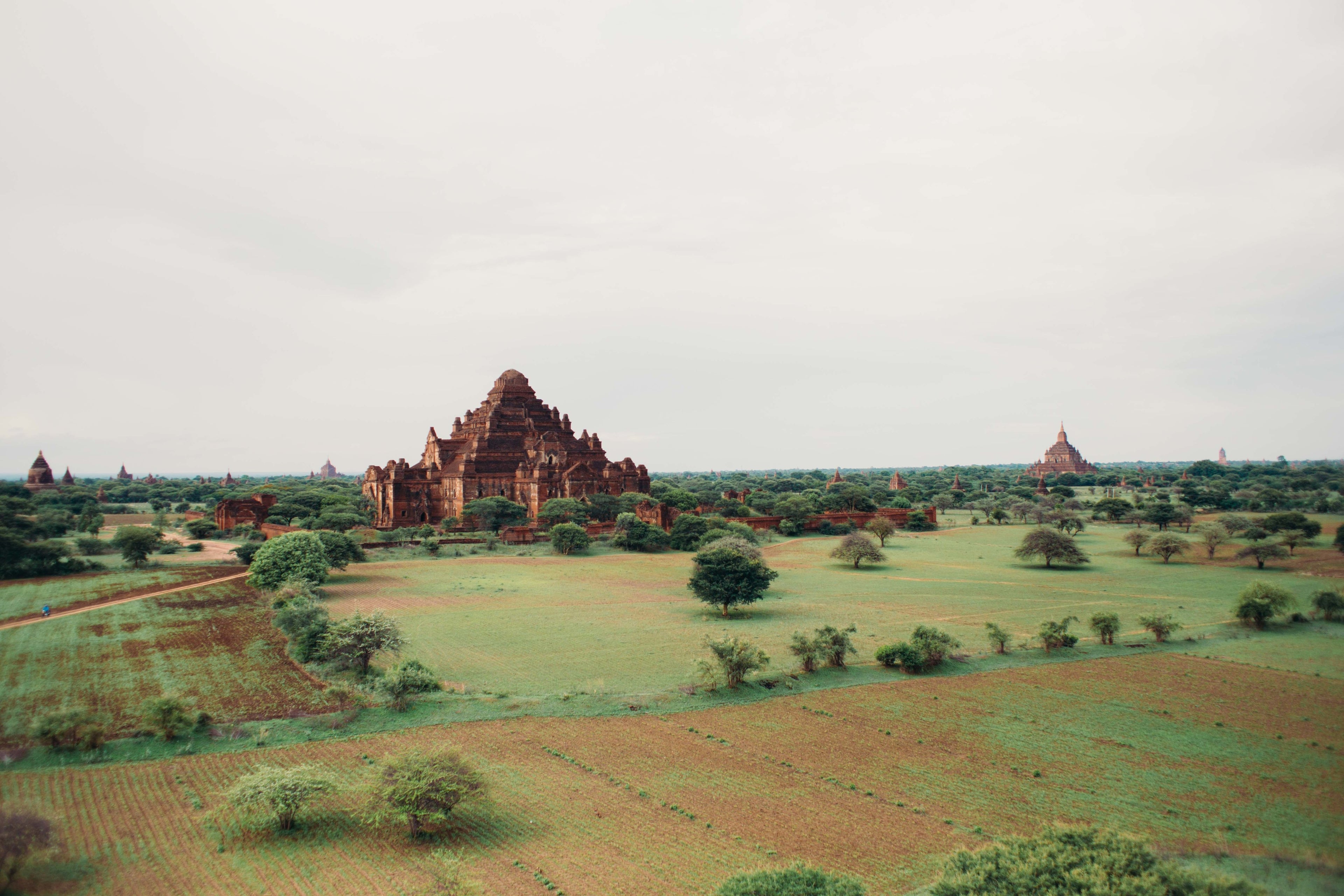 Panoramic view of ancient temples scattered across green plains in Bagan, Myanmar.